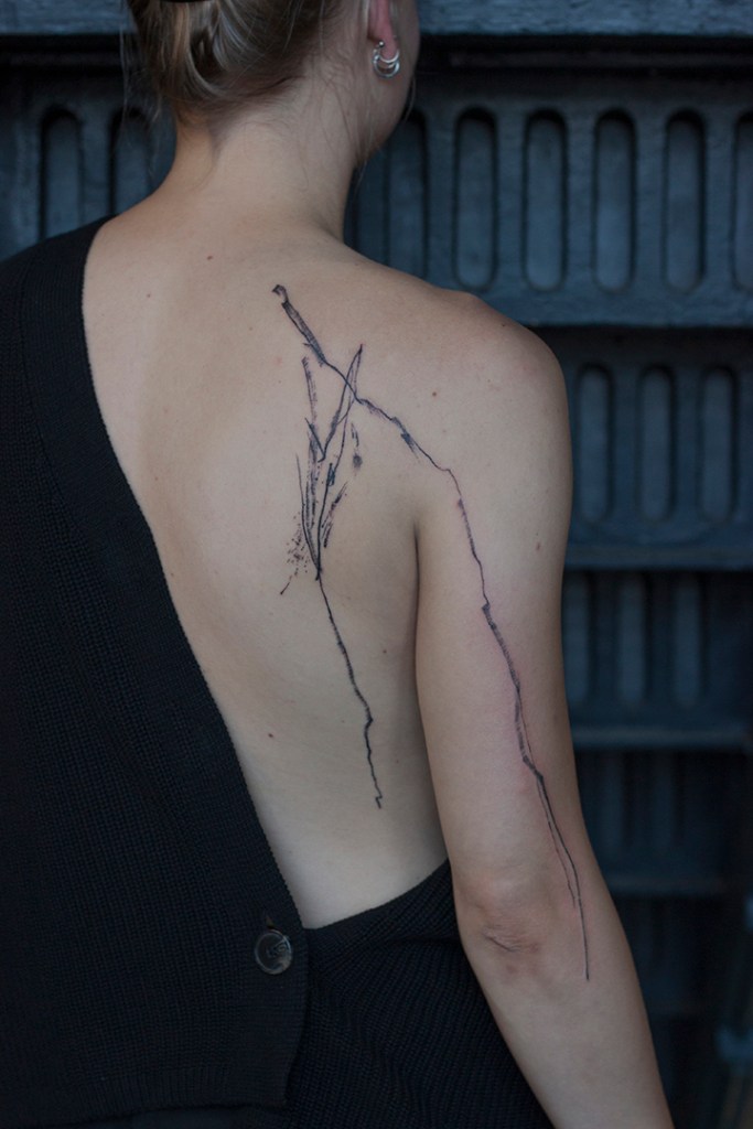 abstracte tattoo op rechterschouder met lijnen die doorlopen naar zij en bovenarm. Lijnen met textuur, alsof het met inkt op het lichaam getekend is