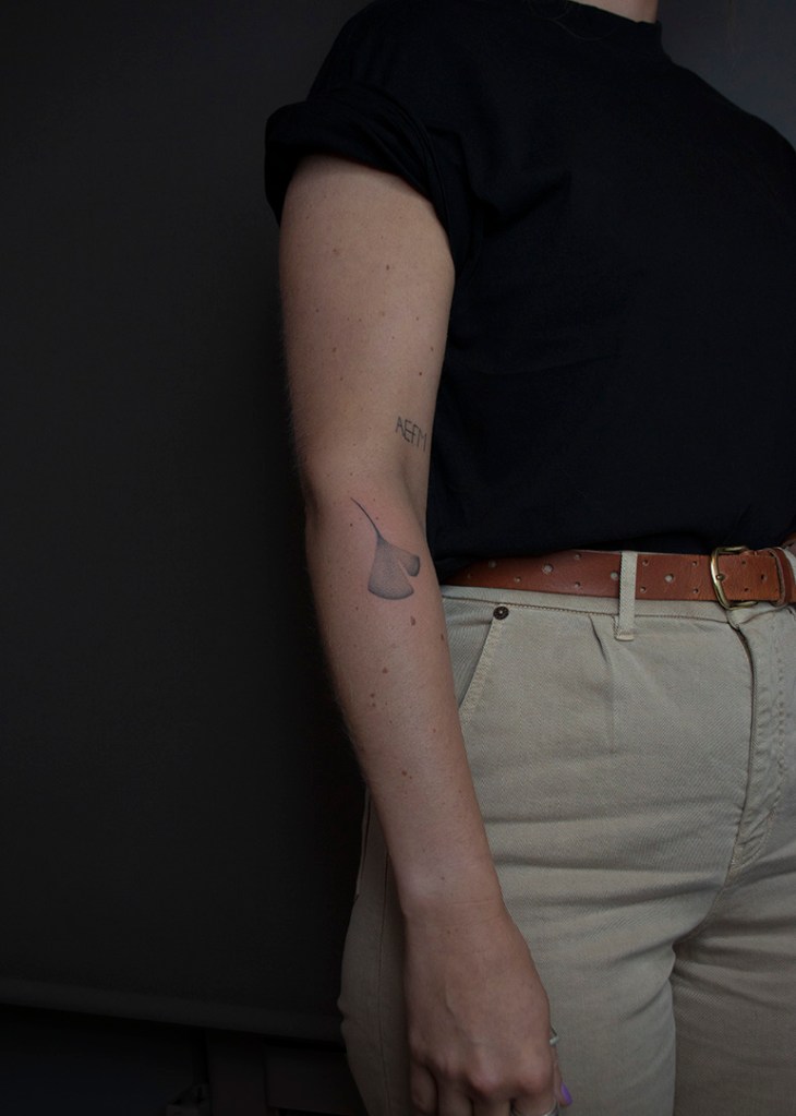 handpoke tattoo van een ginkgo blad op de buitenkant de rechter onderarm, net onder de elleboogsplooi. Het blad ziet er breekbaar uit met veel gradaties